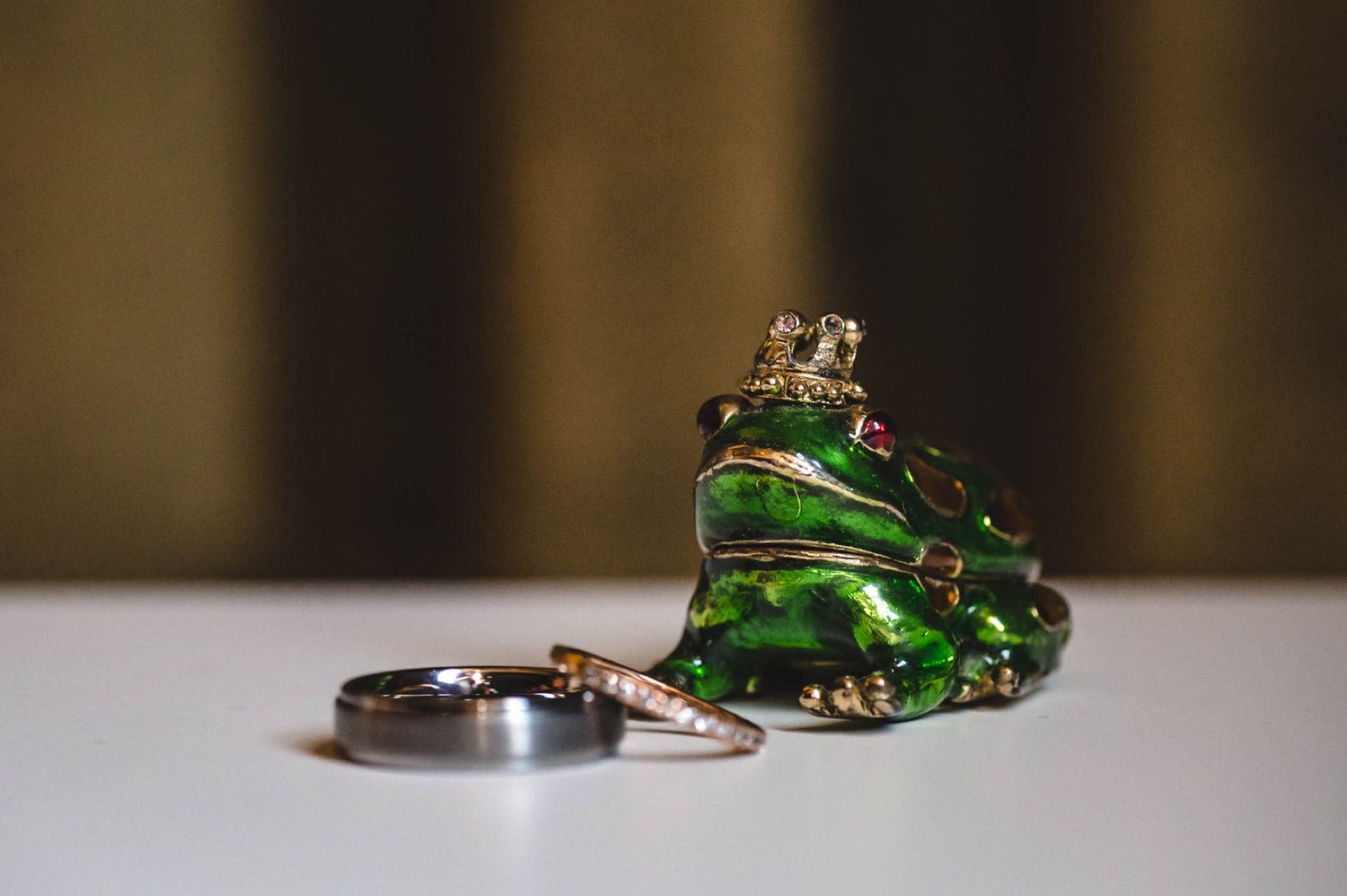 Close-up of emerald green wedding rings on reflective surface.