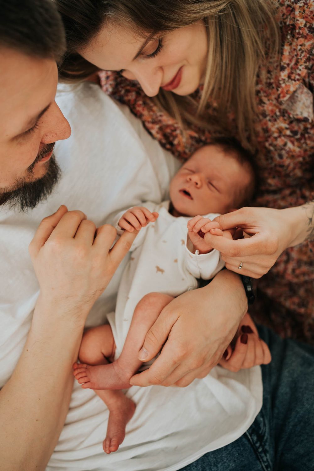mama i tata trzymają za rączki noworodka - fotograf noworodkowy Kraków
