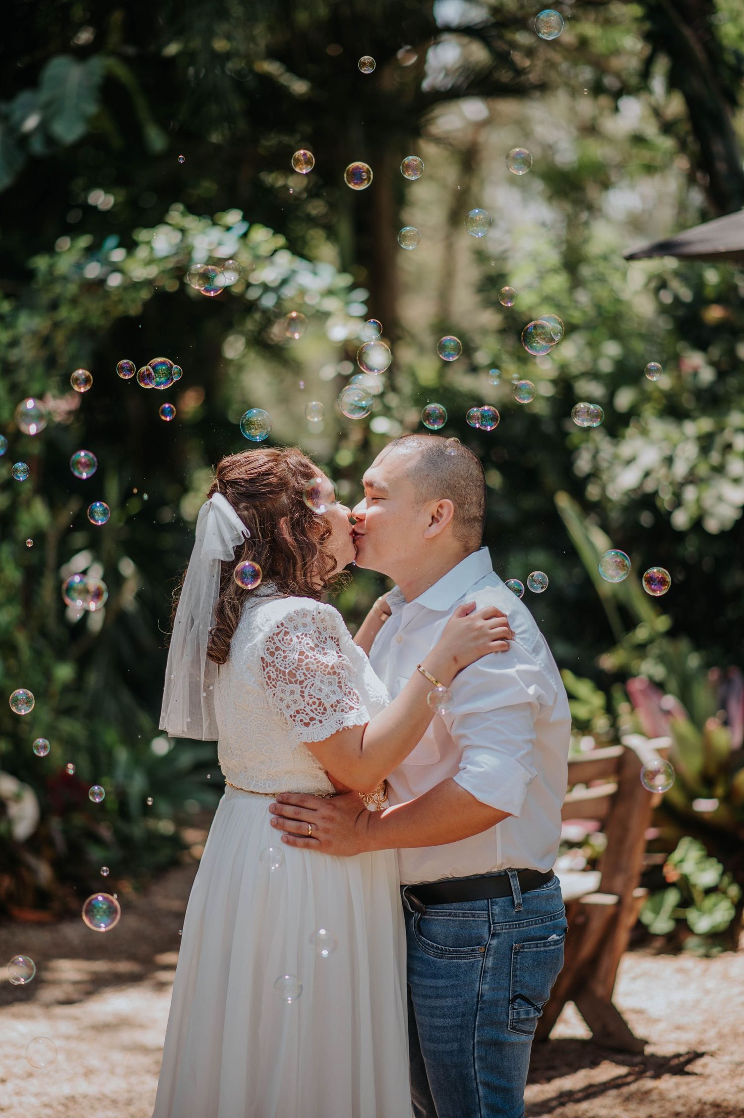 A romantic wedding photo with soap bubbles floating around a kissing couple in a garden.