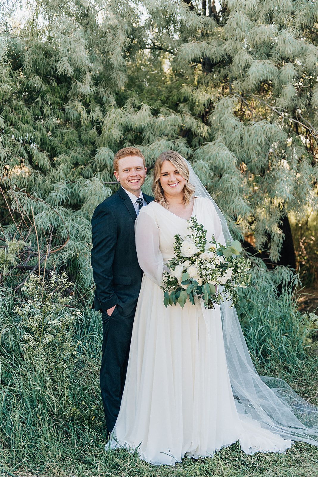 A wedding portrait against a backdrop of silvery green foliage.