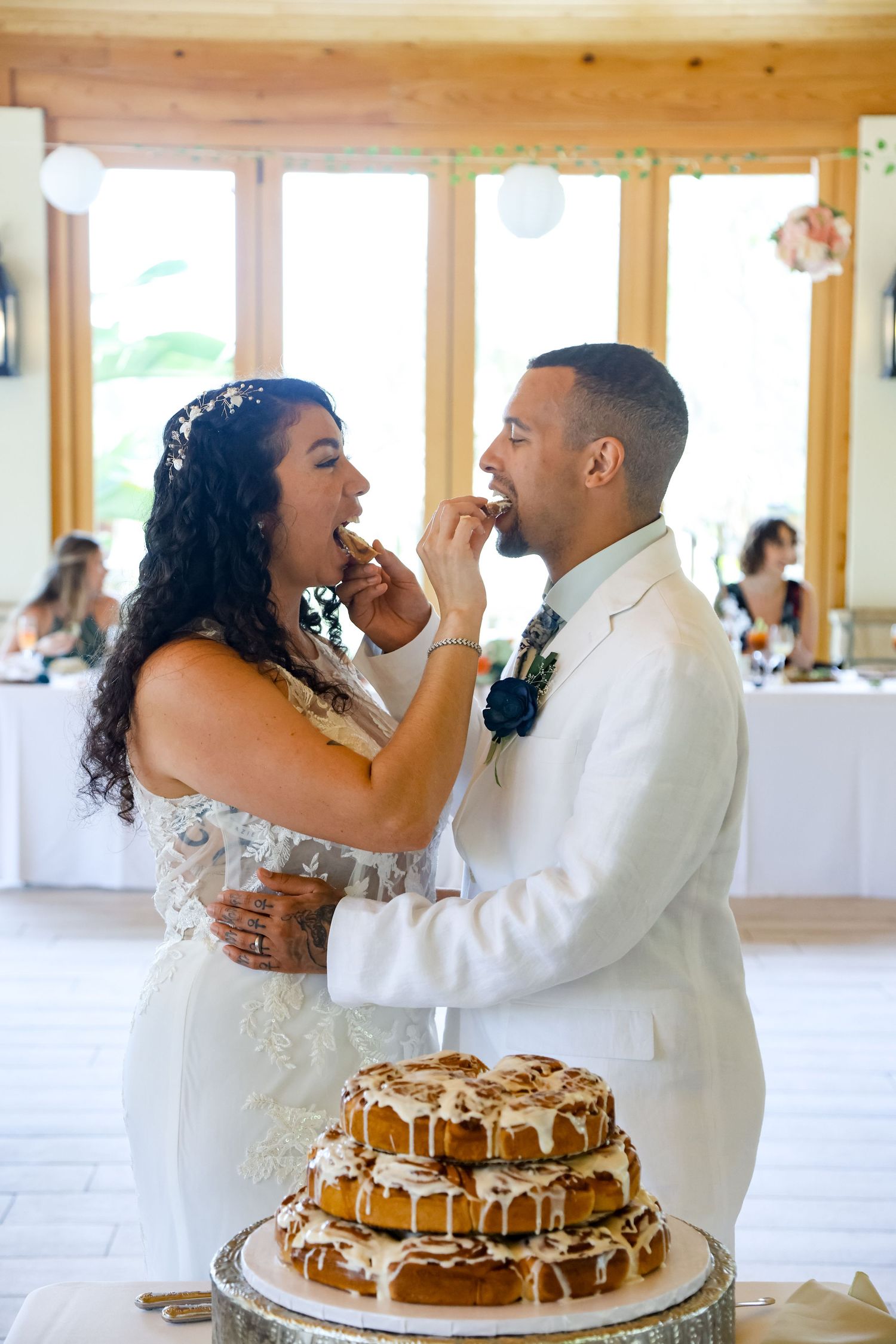 Couple sharing cake at their wedding reception in a rustic wooden venue.