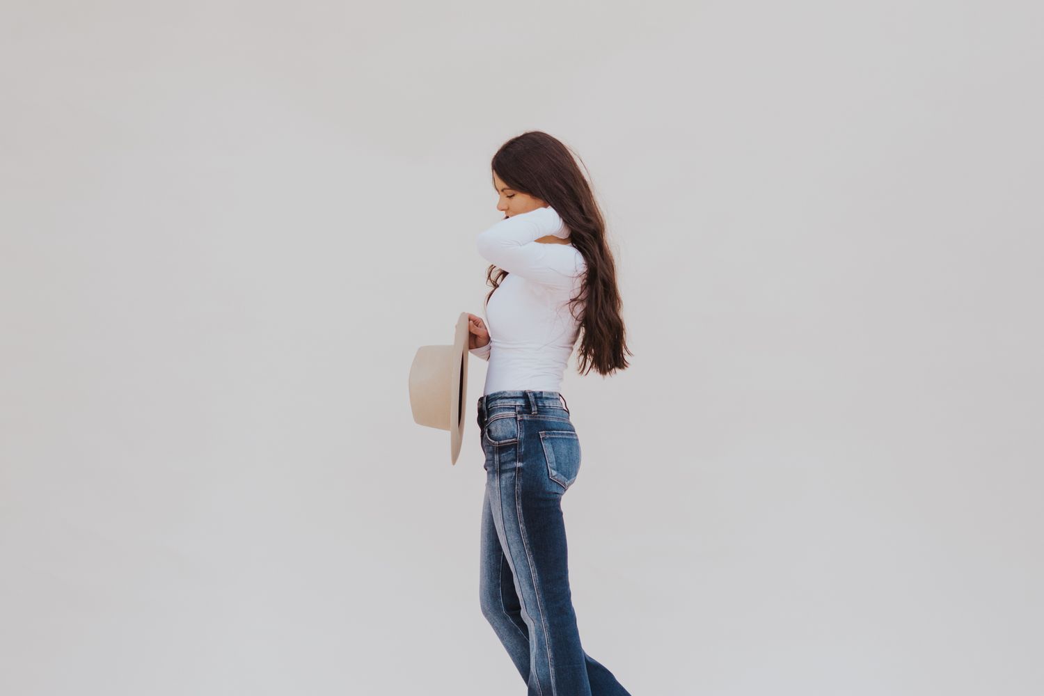 Woman in jeans walking through minimalist white studio space.
