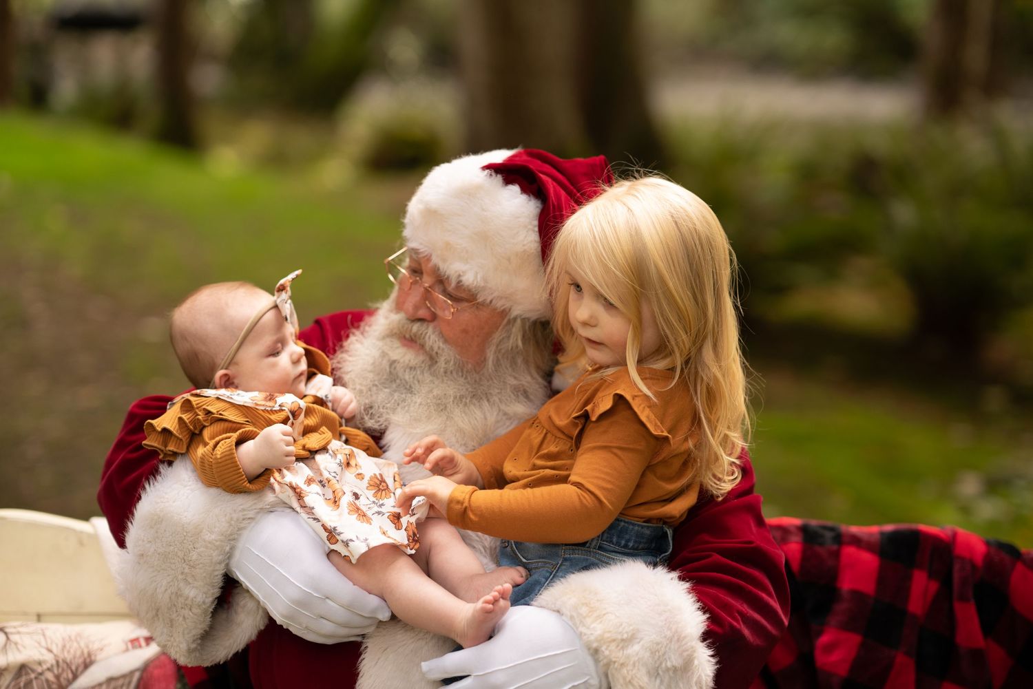Family in cozy winter outfits poses on plaid blanket during holiday photo session.
