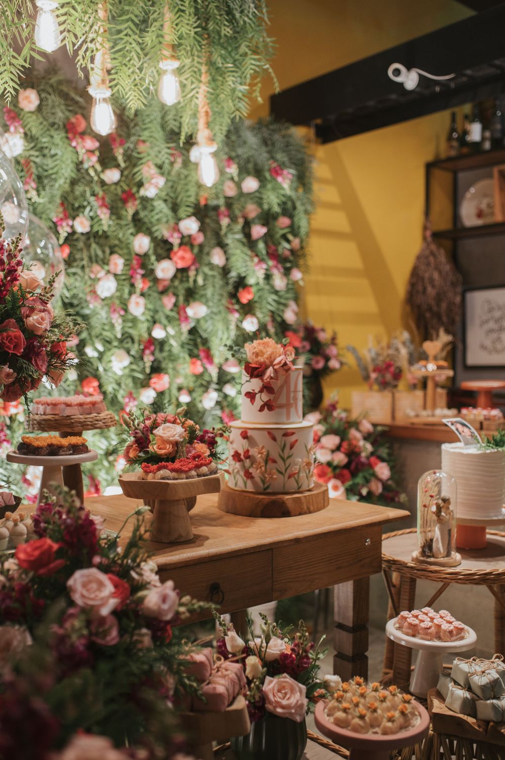 Rustic wedding dessert display with multiple tiers of treats under cascading greenery and flowers.