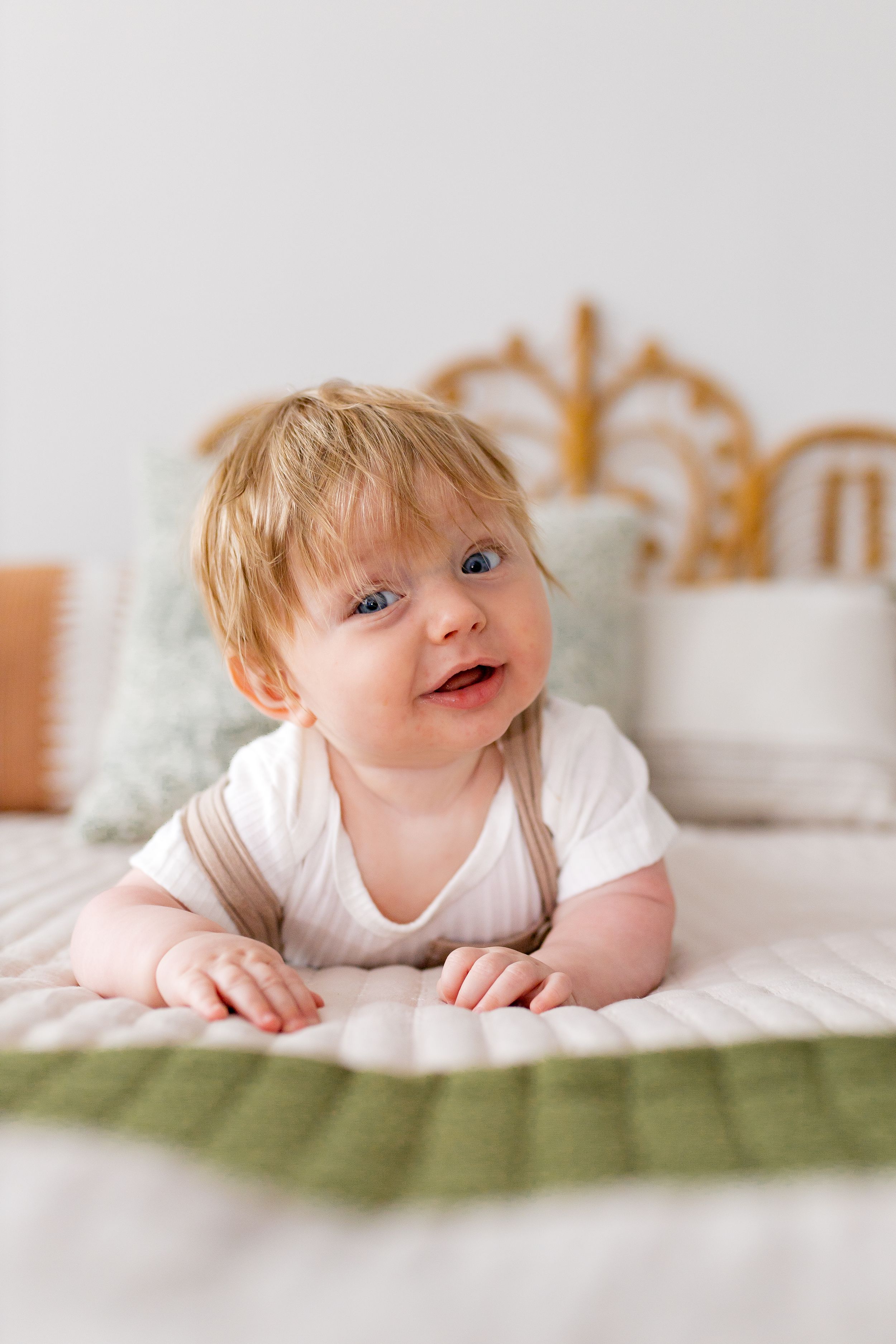 Baby in white onesie smiling on green bedding with decorative headboard.
Janesville, WI
Brodhead, WI