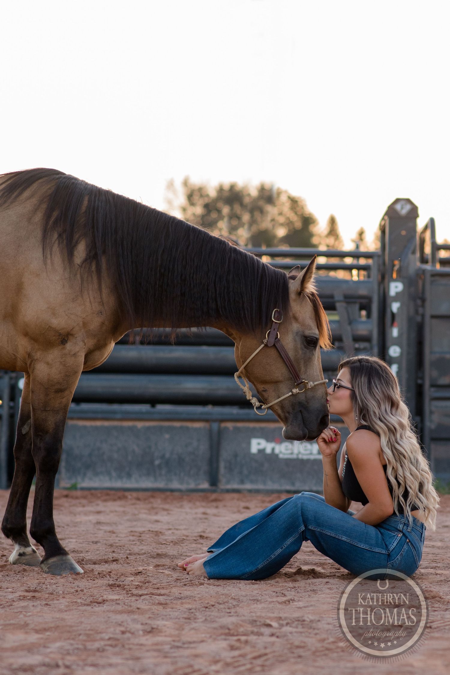 Brown horse and handler share tender moment in rustic arena setting.