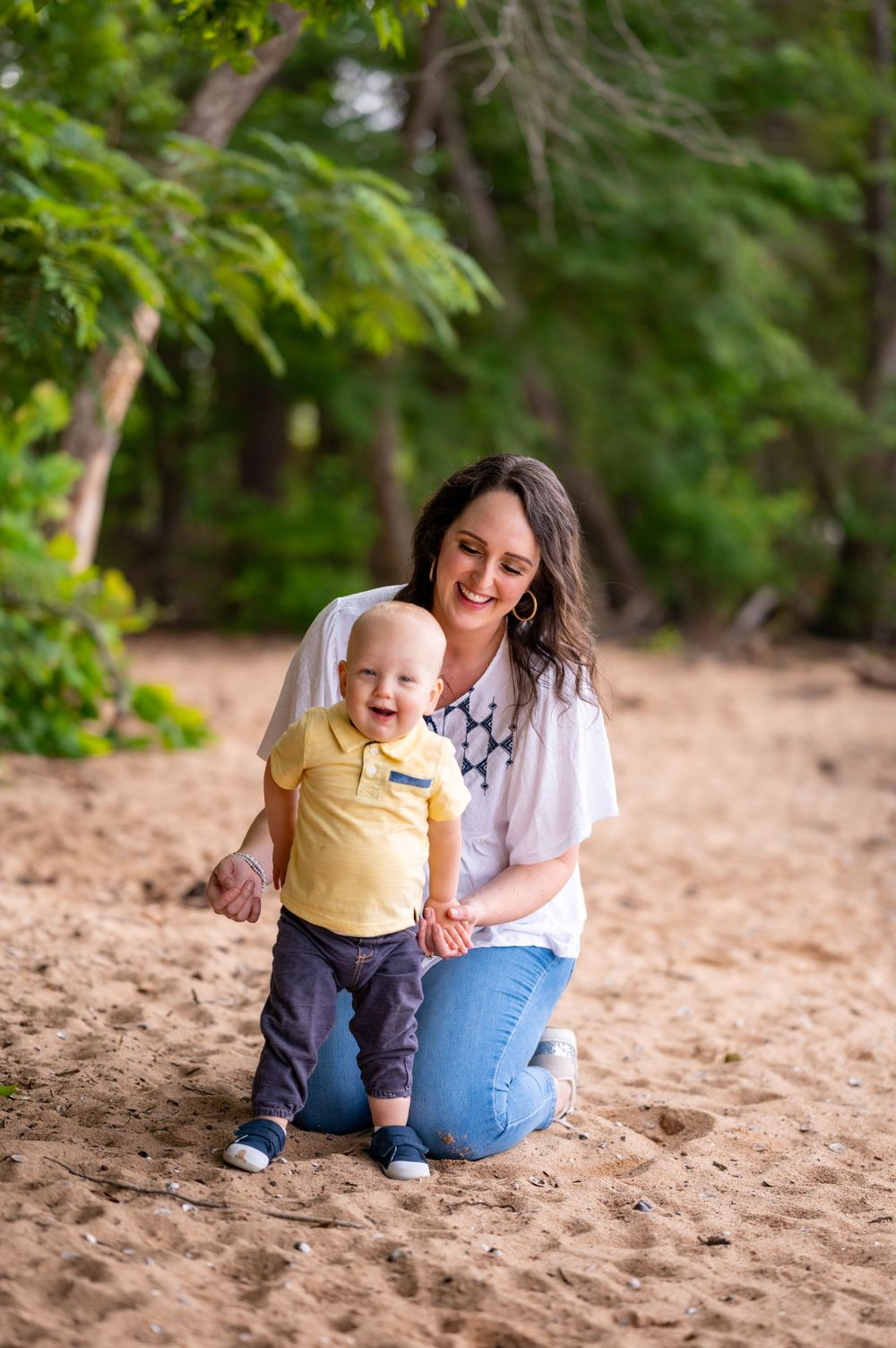 A tender moment shared between parent and child playing on sandy ground in a wooded area.