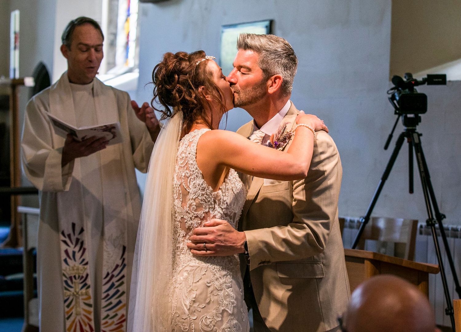 Wedding couple dancing together in a church with stained glass windows visible.