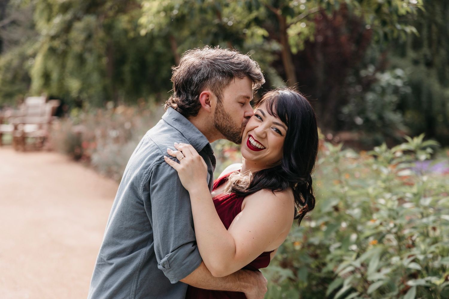Joyful couple sharing romantic moments in a garden setting.