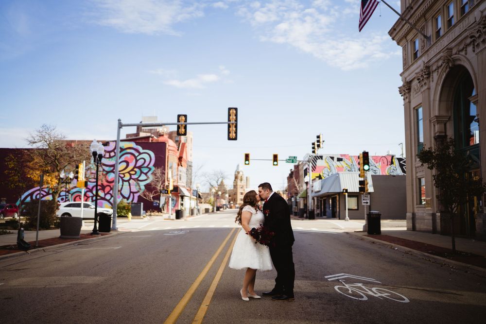Couple sharing romantic moment on empty city street with urban art in background.