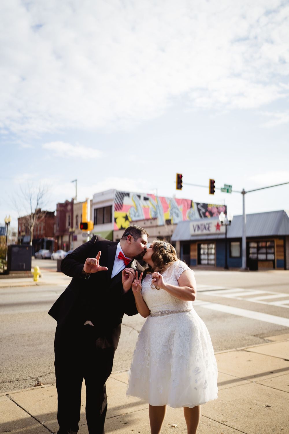 Candid moment between newlyweds on urban street corner with colorful murals.