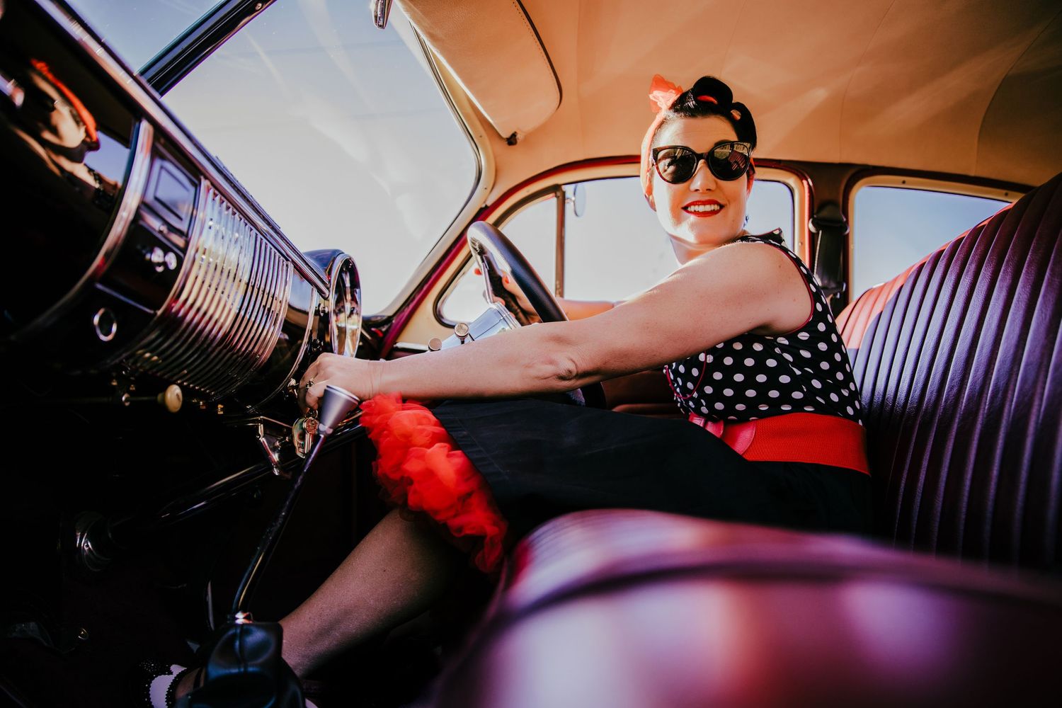 rockabilly fashion dressed lady in a classic car starting the engine