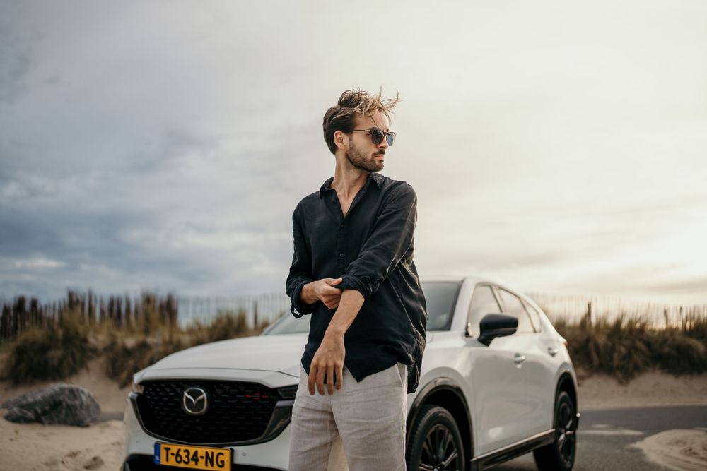 Modern white SUV parked against desert landscape with cloudy sky.