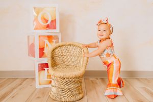 Baby exploring first birthday cake smash setup with woven basket and festive decorations.