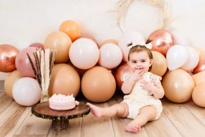 Decorative setup with balloons in neutral tones and wooden accents for baby photography.