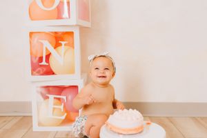 Birthday photoshoot setup with illuminated cake and white frames on neutral background.