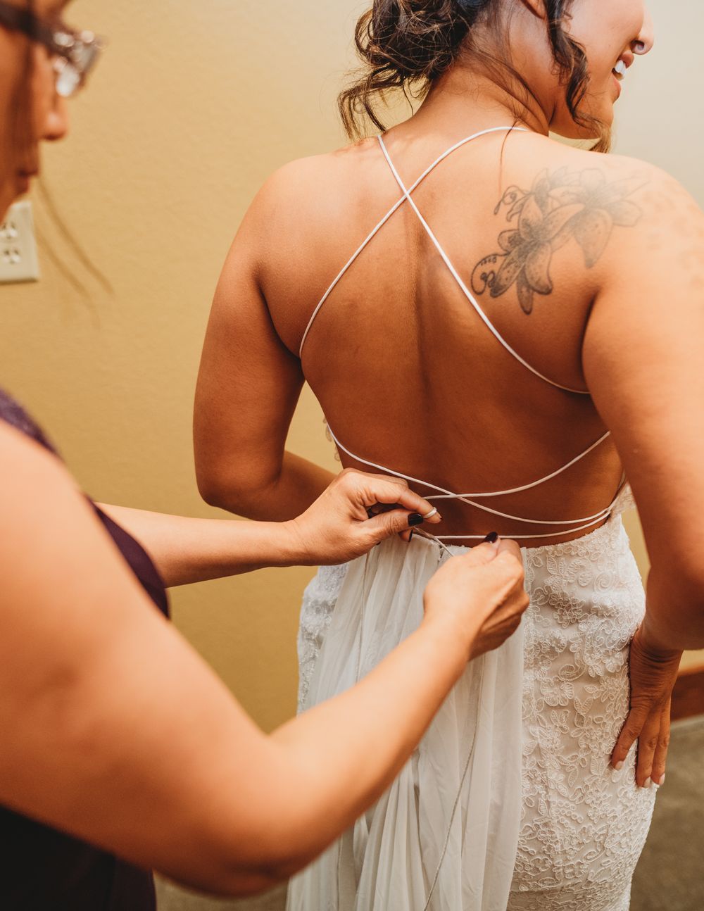 Close-up shots showing the intricate details and lacing of a white wedding dress being fastened.