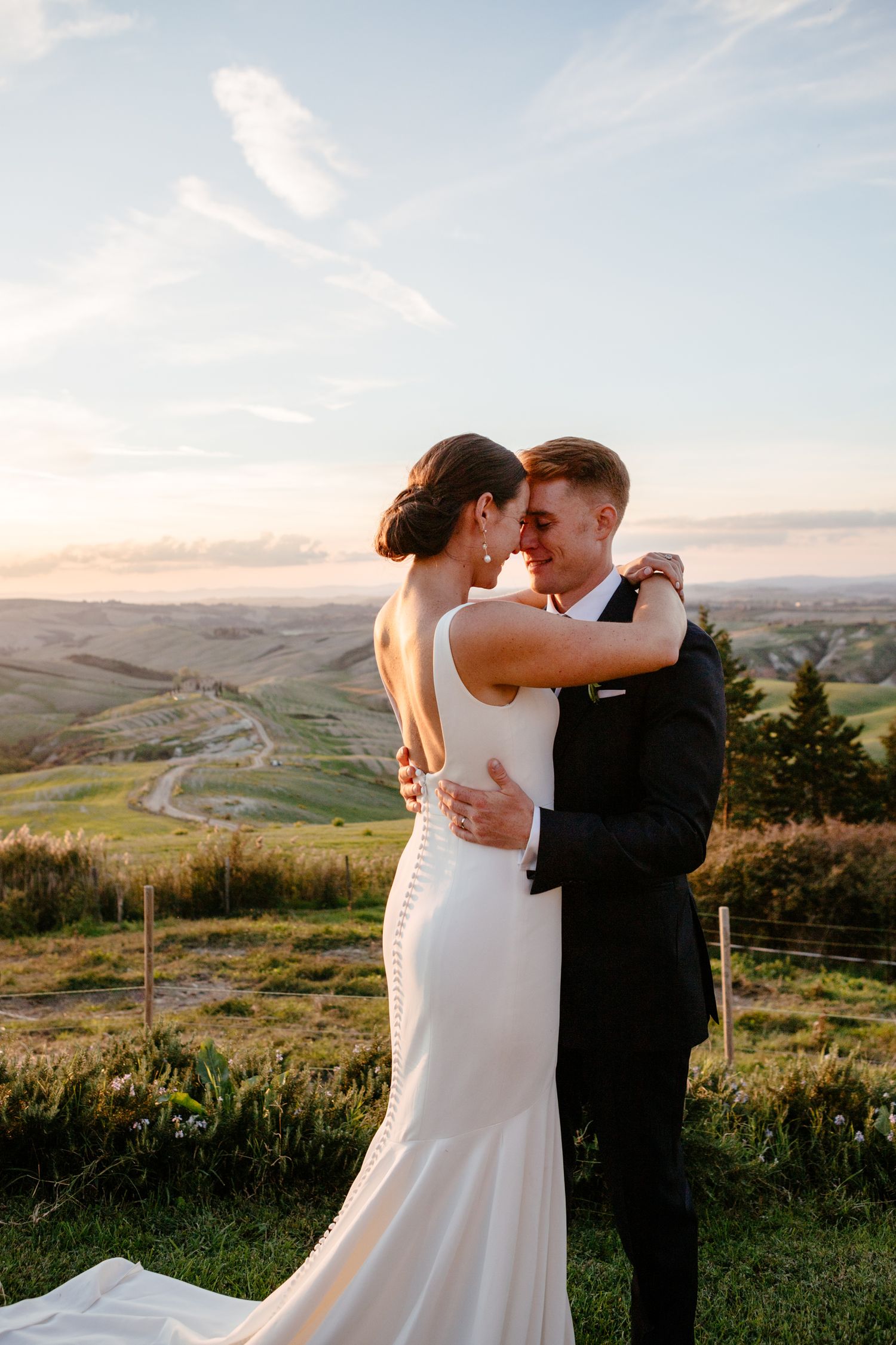 A bride and groom take a moment as the sun sets with the rolling hills of Siena as their backdrop.