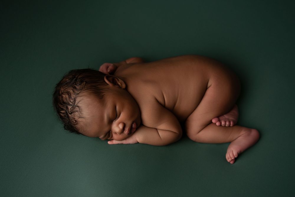 Newborn laying on green backdrop -Pueblo, Colorado Newborn Photographer