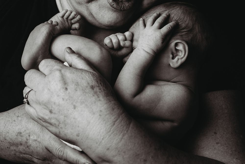 Newborn curled in grandmother hands -Pueblo, Colorado Newborn Photographer