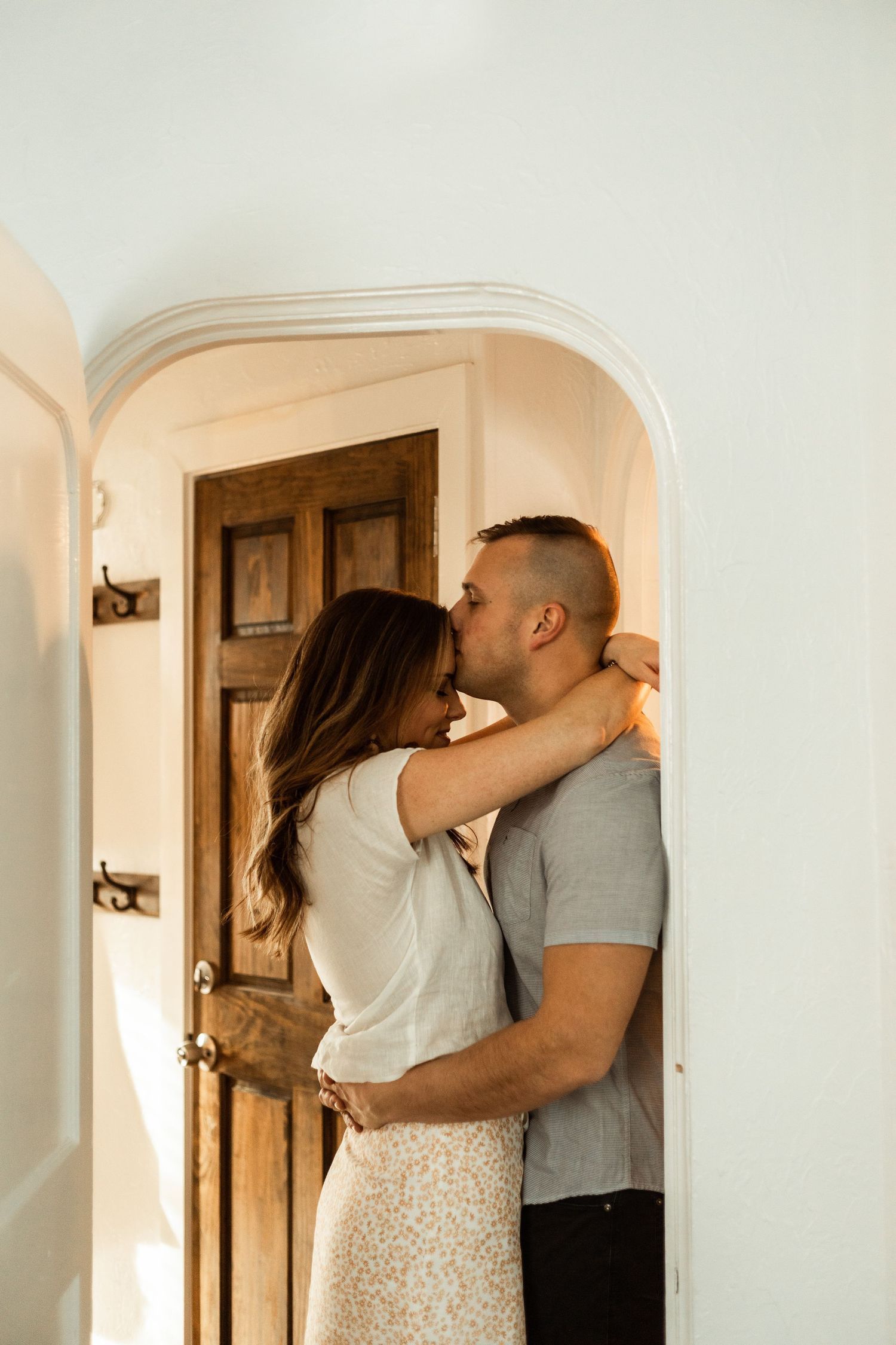 An intimate moment between a couple embracing in a doorway with warm lighting.