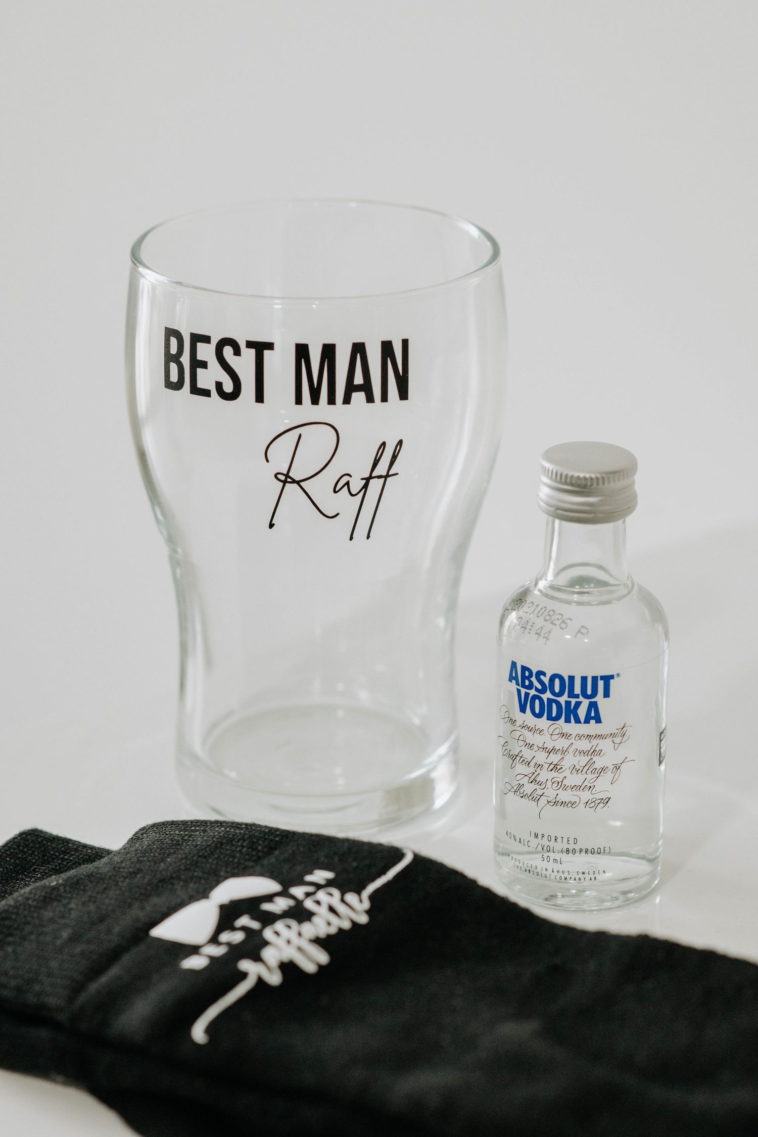 A personalized Best Man glass with a miniature Absolut vodka bottle and black sock.