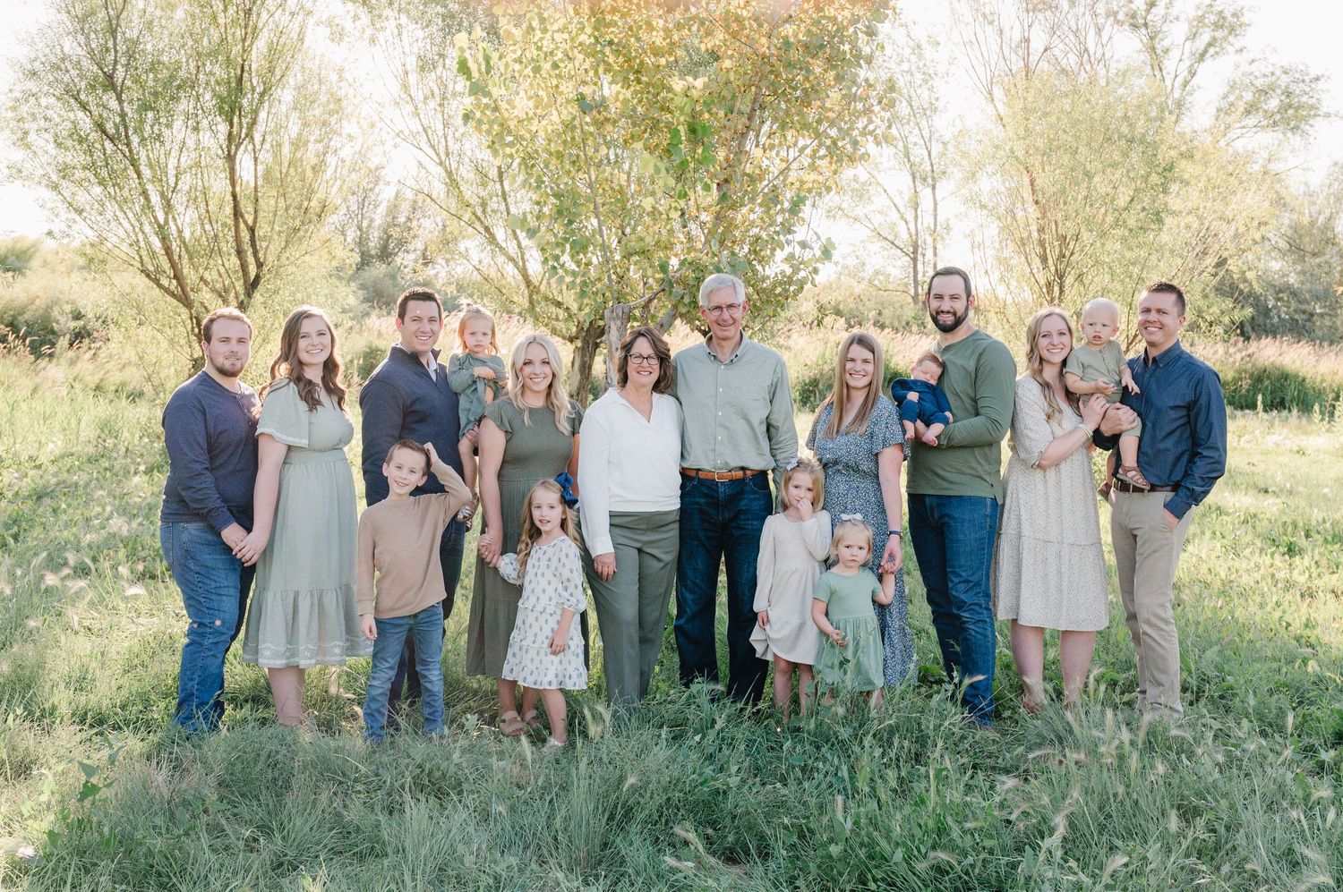 Extended family gathering outdoors for a group portrait in autumn setting.