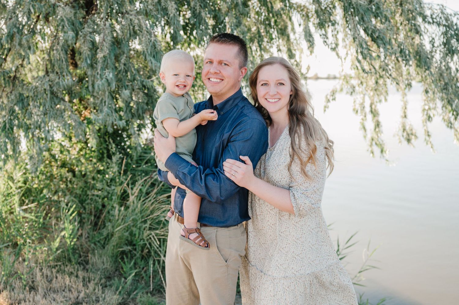 Family portrait by water with willow trees and natural afternoon lighting.