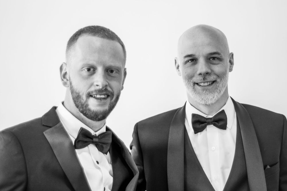 Black and white formal portrait of men in tuxedos and bow ties.