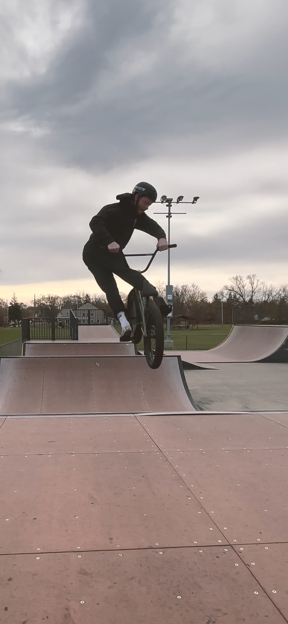 Sequence of skateboarding tricks performed at a skate park during overcast weather.
