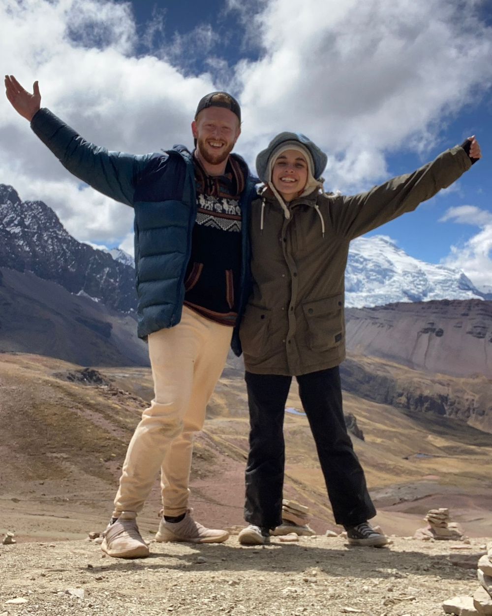 People posing together on a mountain path with snow-capped peaks in the background.