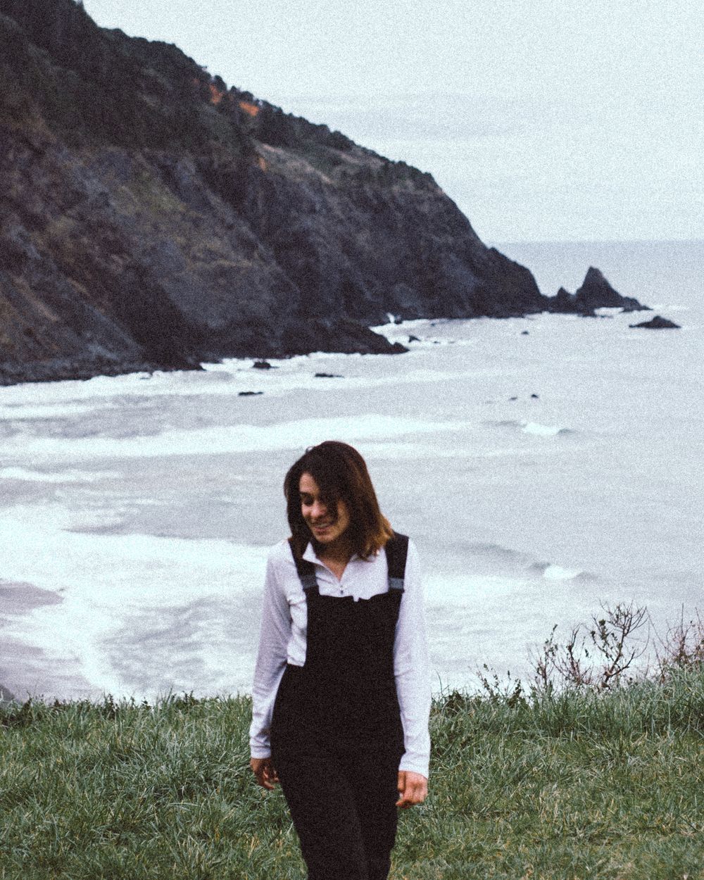 Rugged coastal landscape with rocky cliffs overlooking a misty ocean.