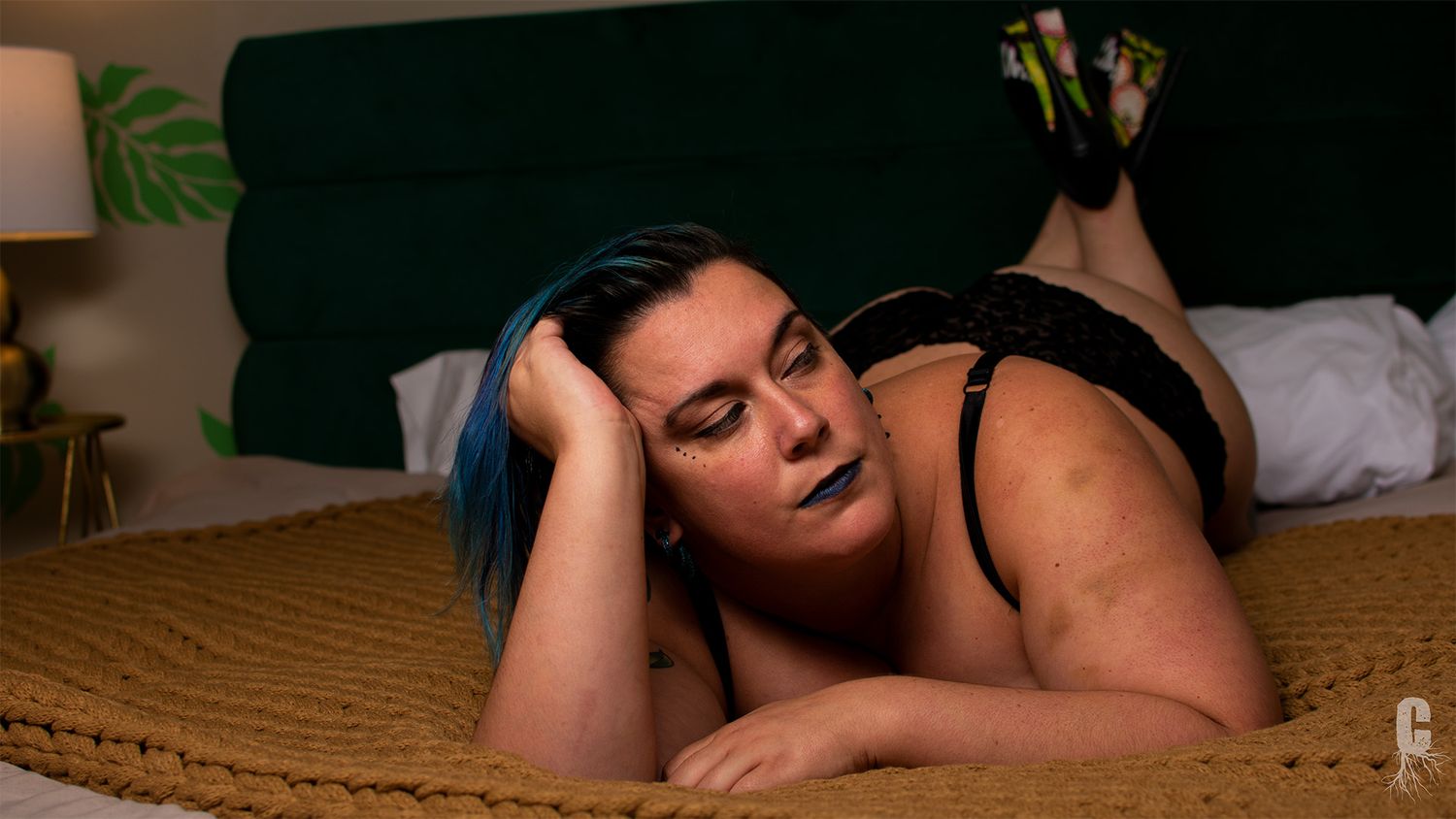 A boudoir model pushing up off of the bed and looking soulfully off camera