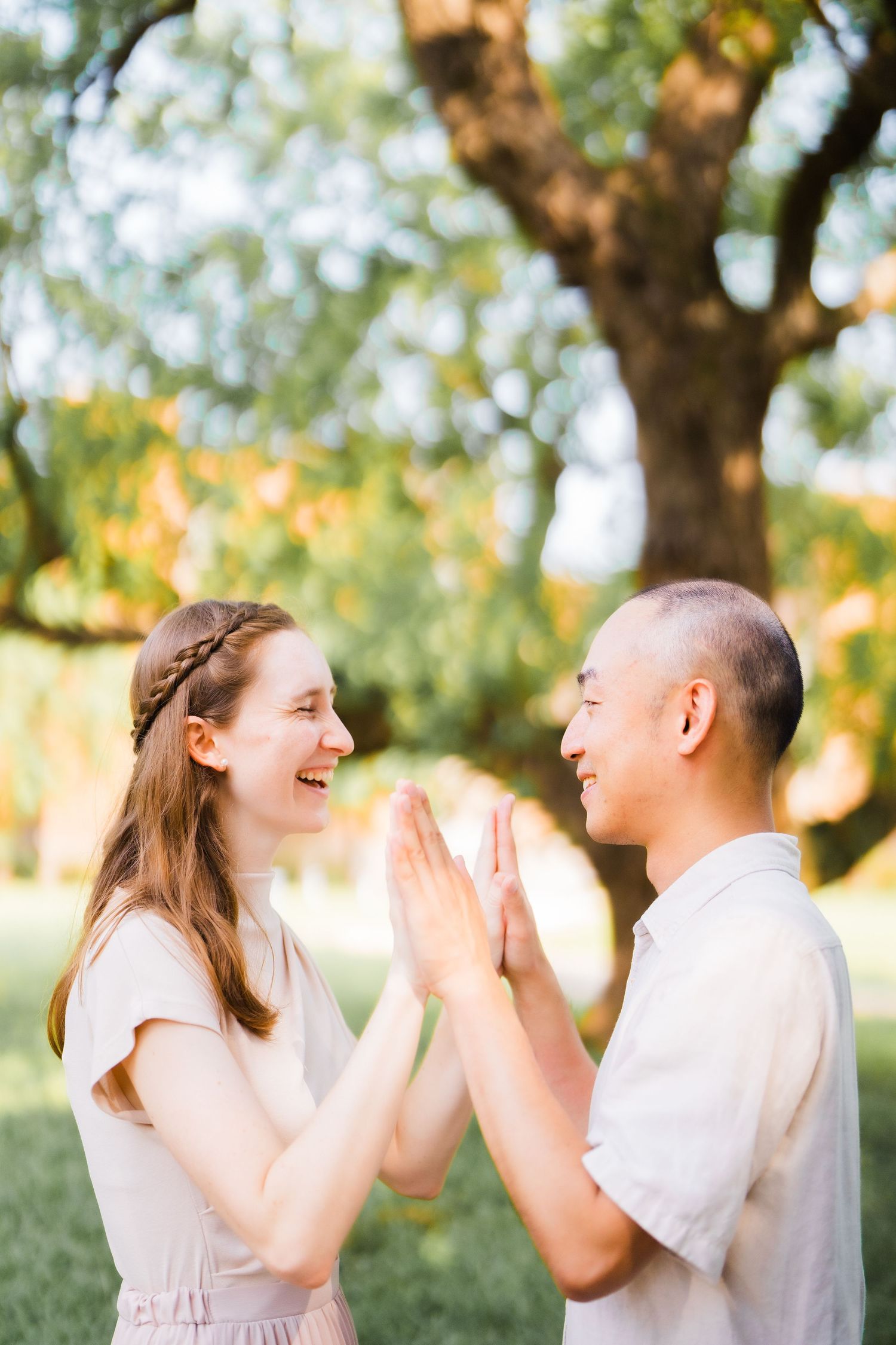 A joyful couple playing pat-a-cake outdoors in a sunny garden setting.