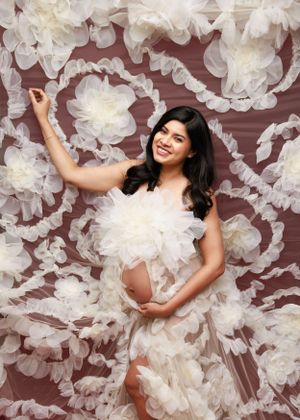 Ethereal maternity portrait with white tulle flowers creating romantic backdrop.