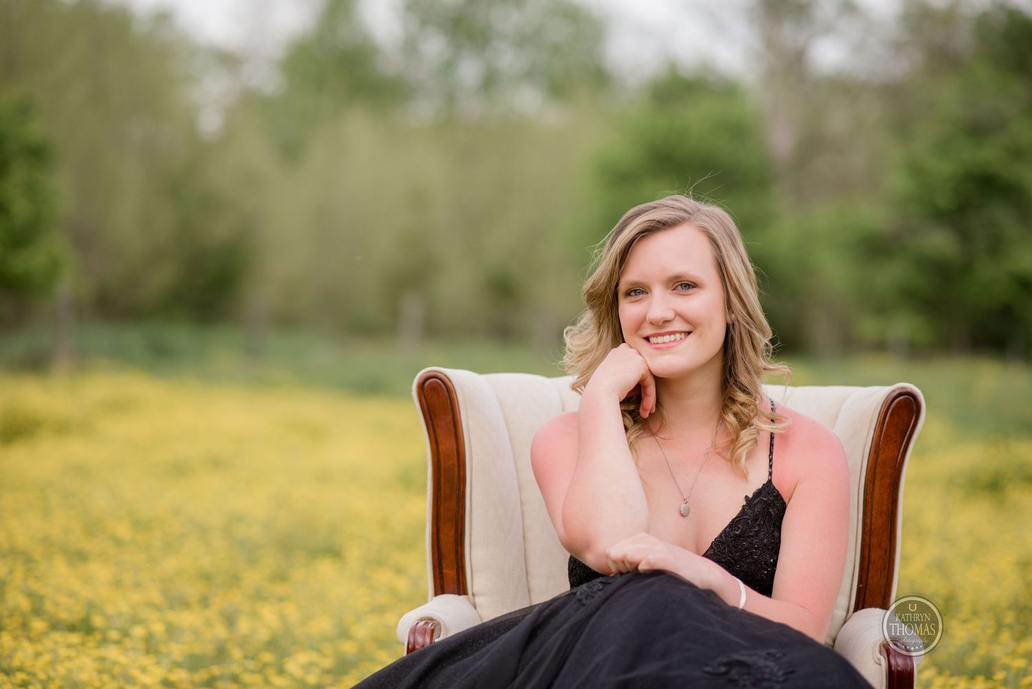 Someone smiles while sitting in a vintage chair surrounded by yellow wildflowers.