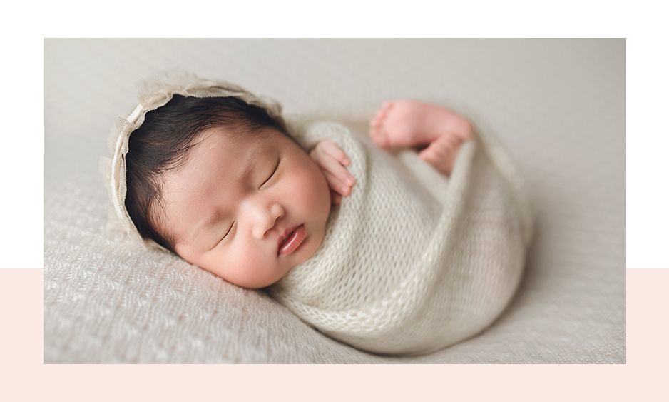 A little Asian newborn baby girl newborn session. On a neutral tan backdrop with a lace bonnet and wrapped newborn pose. In Greenville, SC