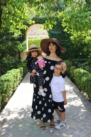 Family in coordinated polka dot outfits posing in a garden archway.