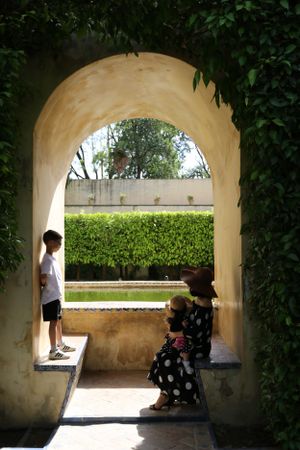 Two people resting in an arched garden passageway.
