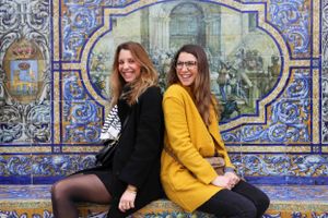 Friends sitting and laughing against a decorative blue tiled wall with intricate patterns.