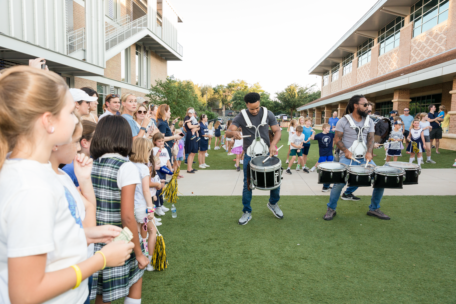 Large group of people gathered outdoors on a grassy area for a social event during daytime.