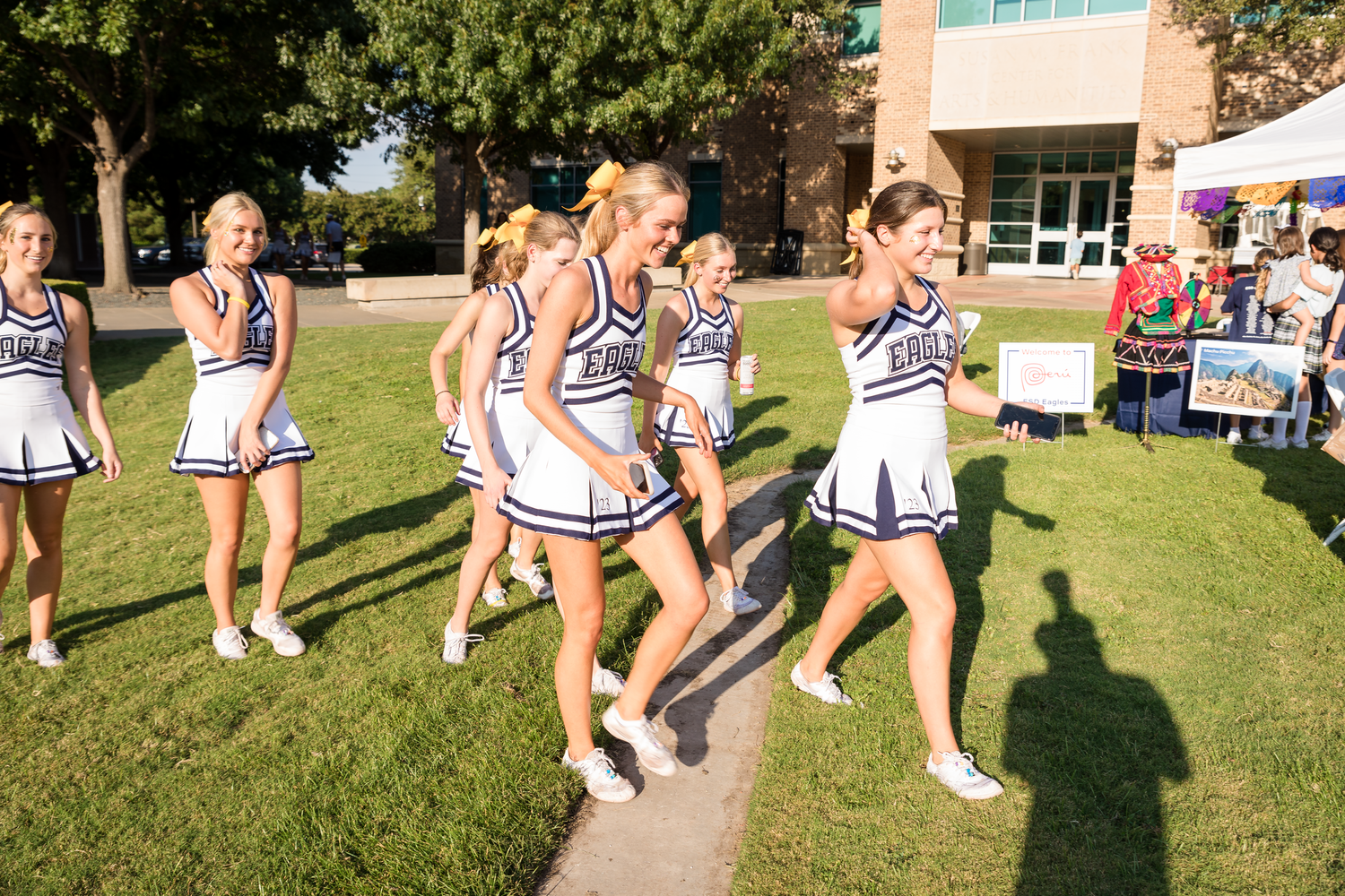 Cheerleaders performing on a sunny day at an outdoor event.