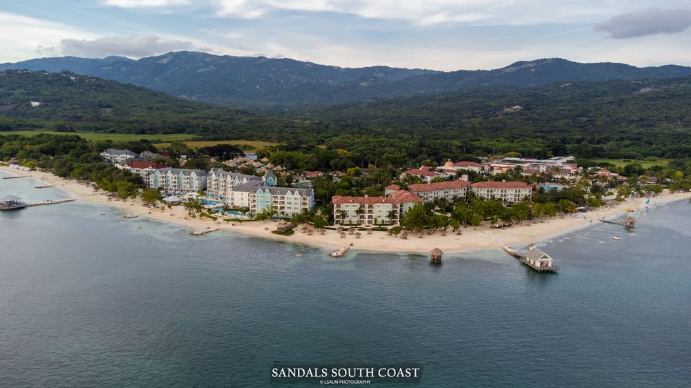 Aerial view of beachfront resort buildings along tropical coastline.