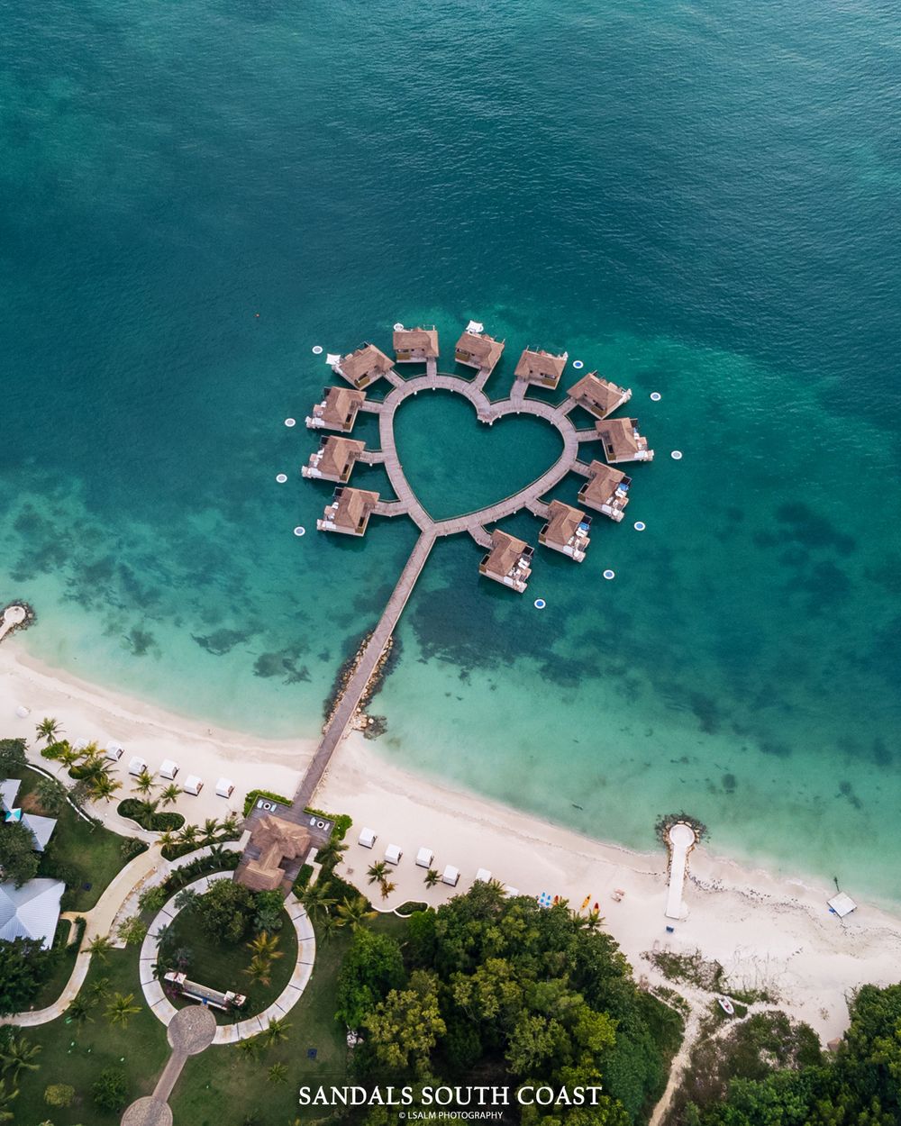 Heart-shaped overwater bungalows at luxury resort viewed from above.