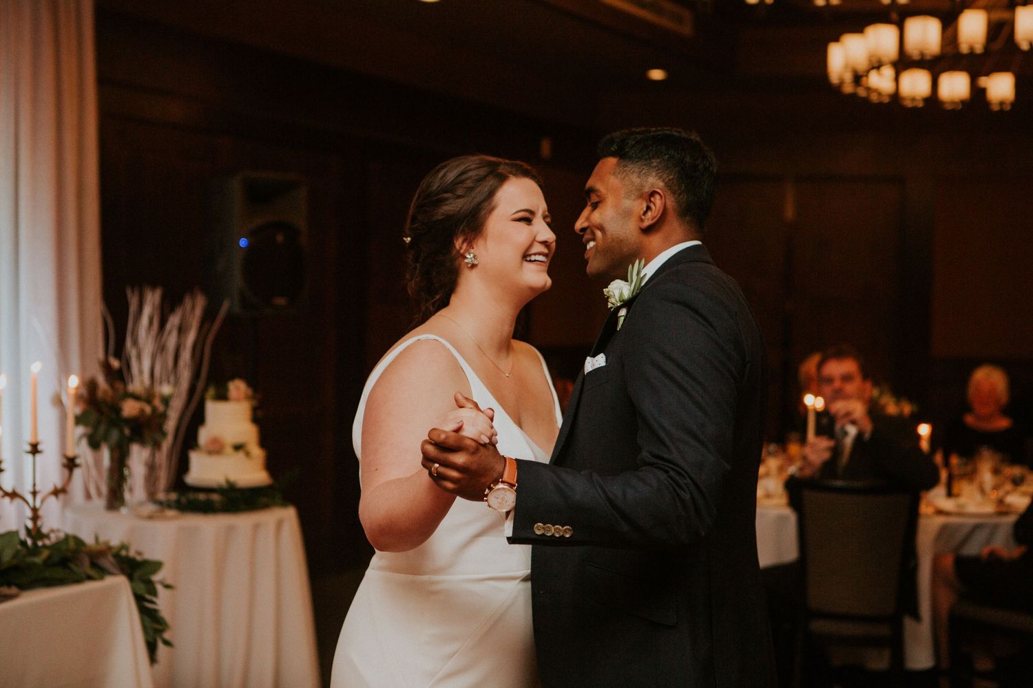 A couple dances intimately together during their wedding celebration in a warmly lit reception venue.
