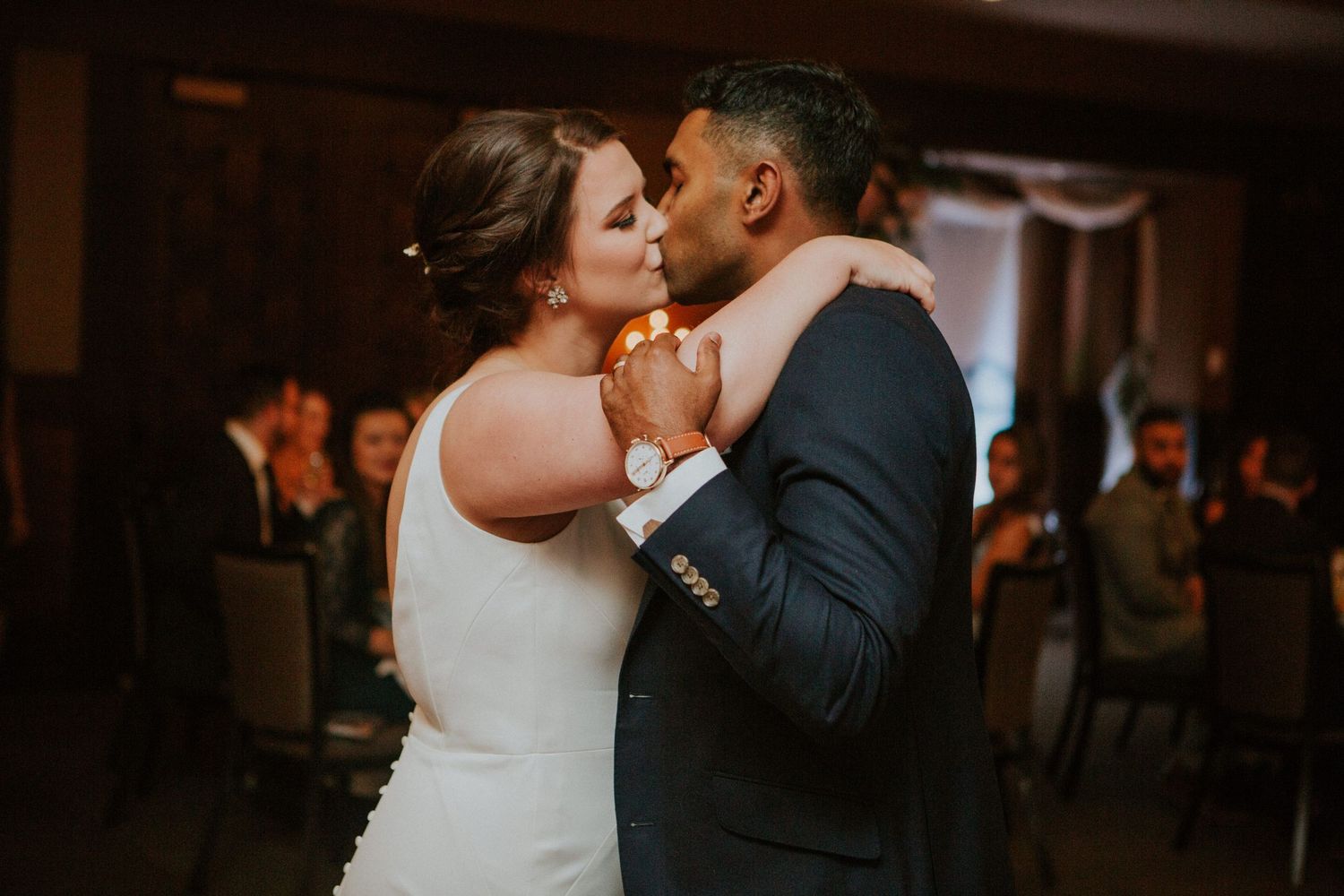A romantic dance moment captured between newlyweds on their wedding day in a dimly lit ballroom.