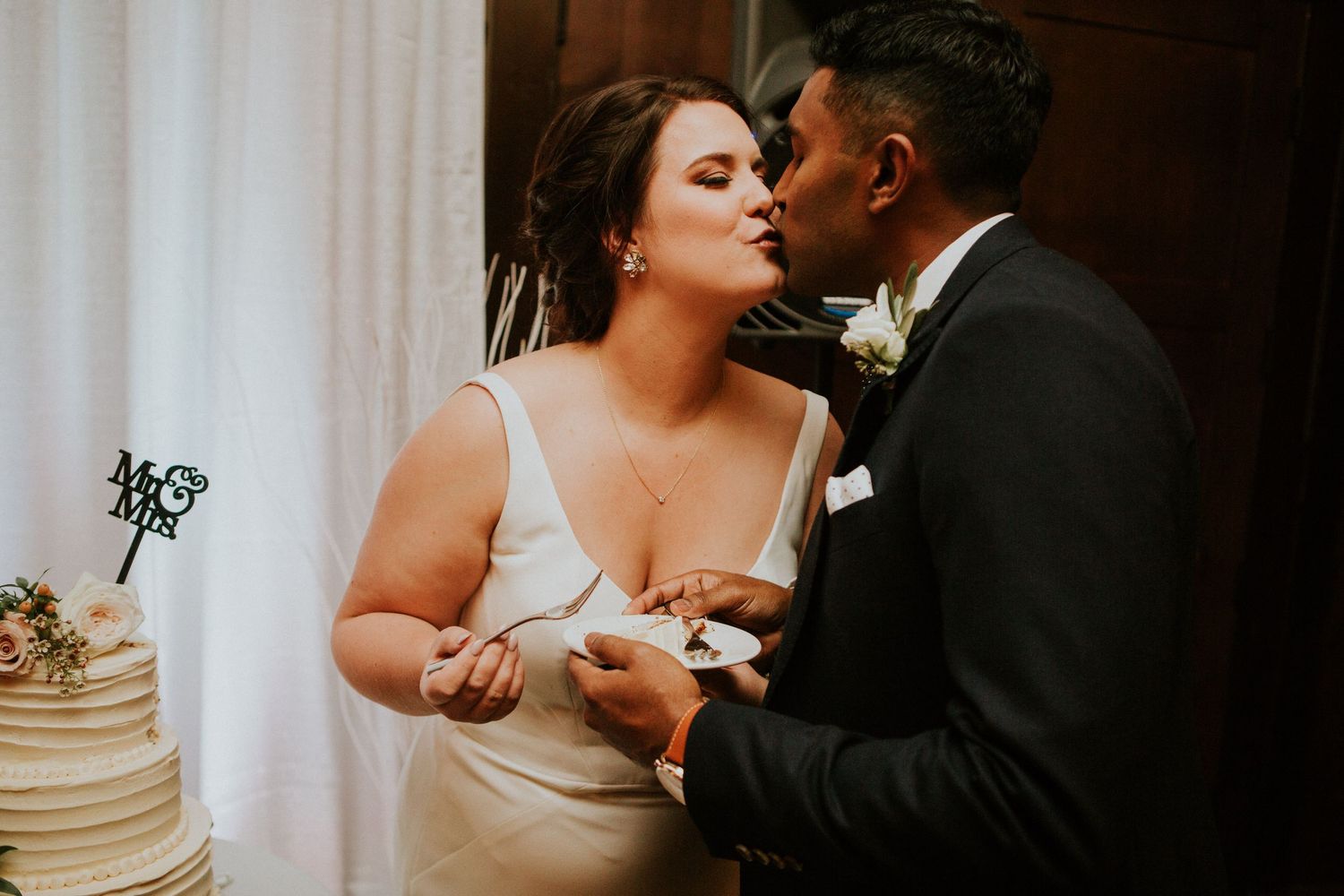 A couple shares an intimate moment while cutting their wedding cake.