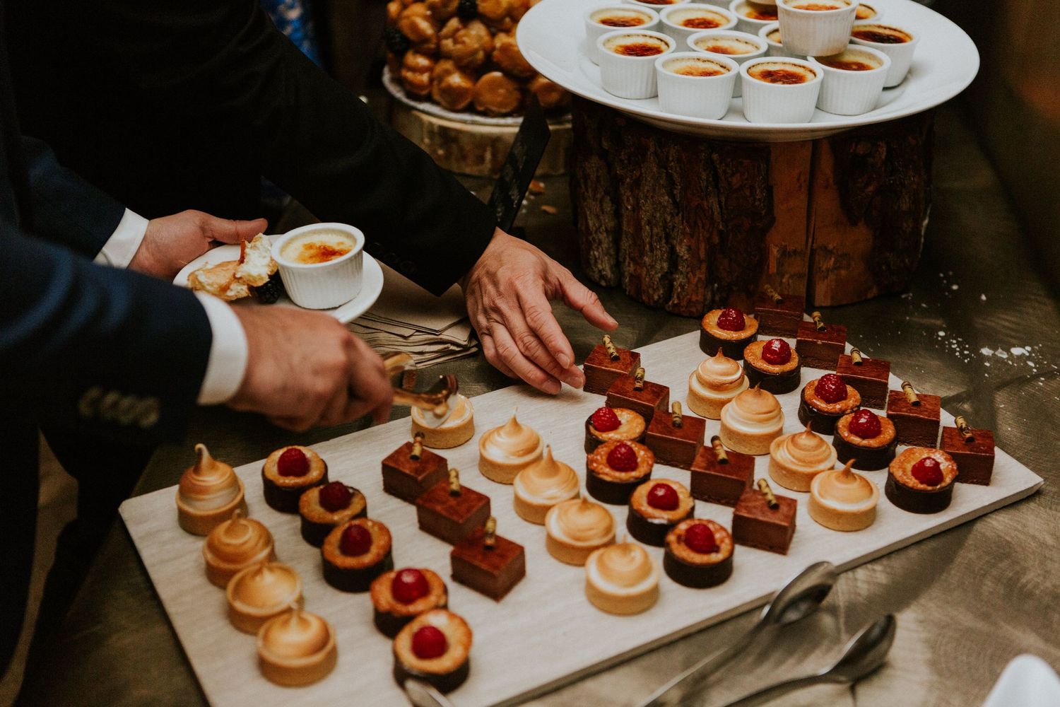 An assortment of colorful mini desserts and pastries arranged on serving platters at a wedding reception.