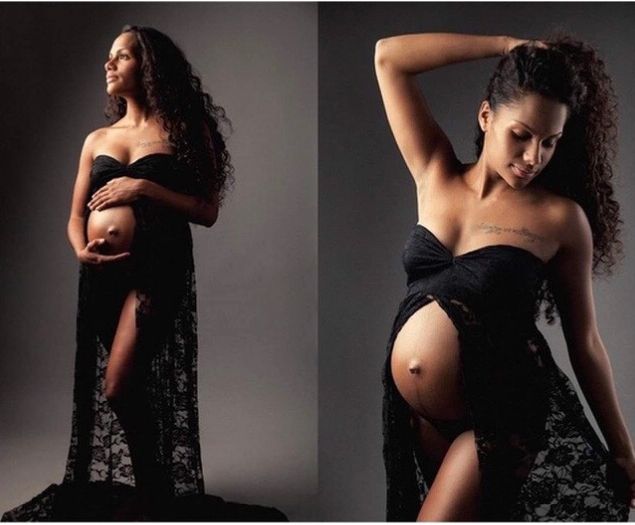 Pregnant woman in a black lace strapless maternity gown posing in a professional studio shoot.