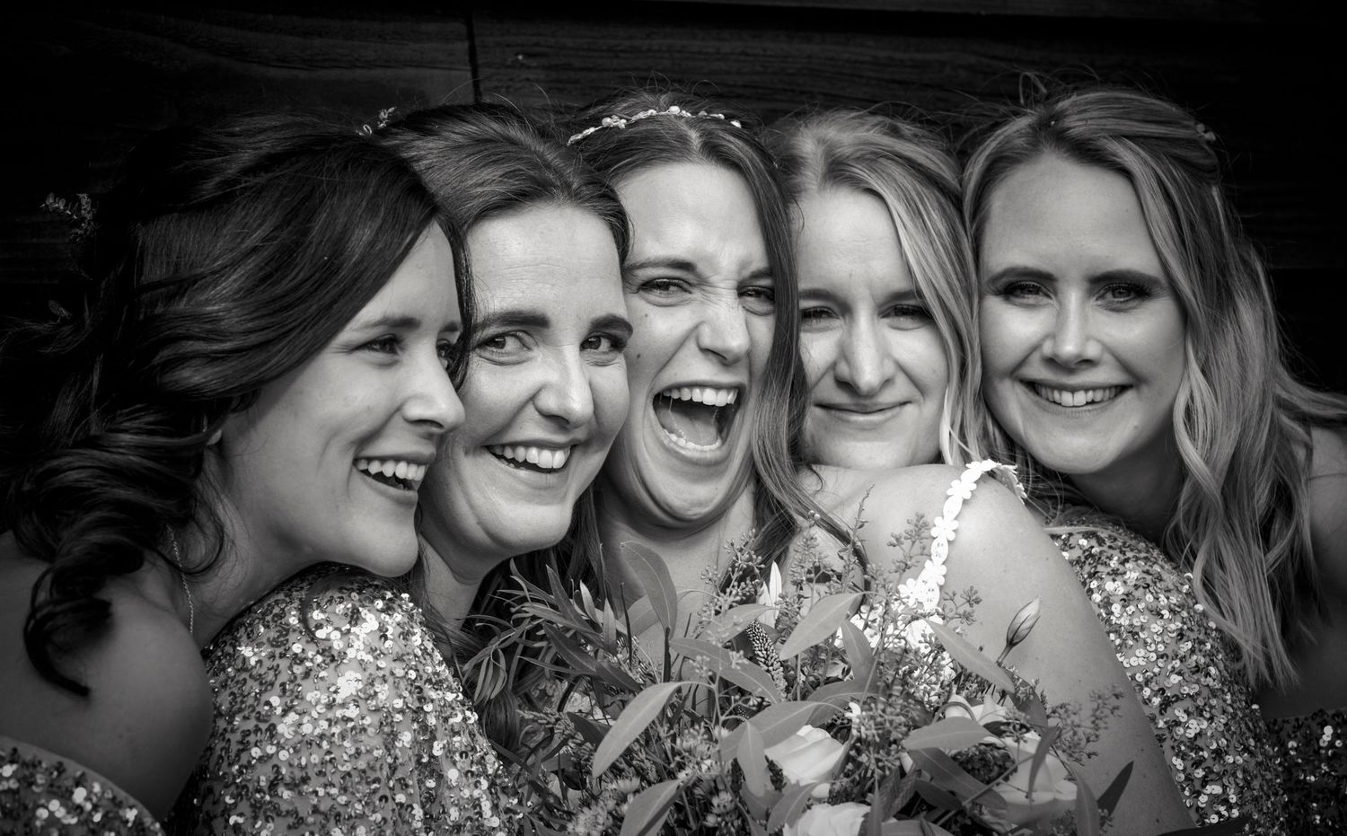 Black and white portrait of wedding party sharing joyful laughter together.